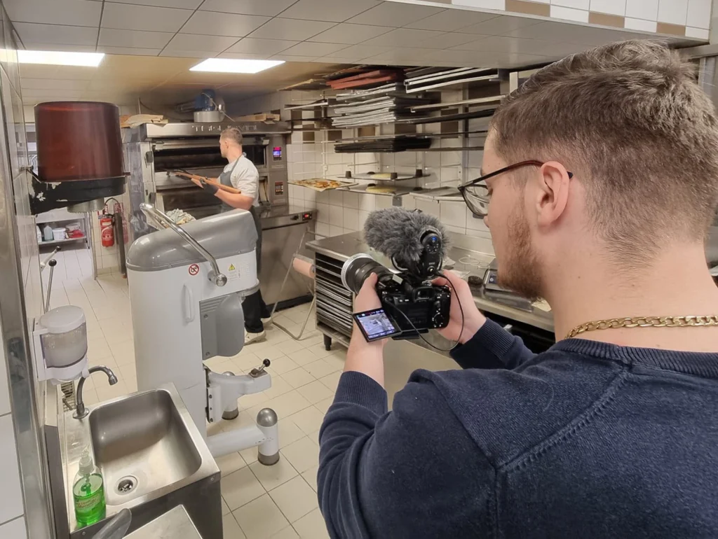 Personne tenant une caméra professionnelle en train de filmer un reportage, illustrant la section vidéo de la page d’accueil