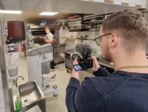 Personne tenant une caméra professionnelle en train de filmer un reportage, illustrant la section vidéo de la page d’accueil