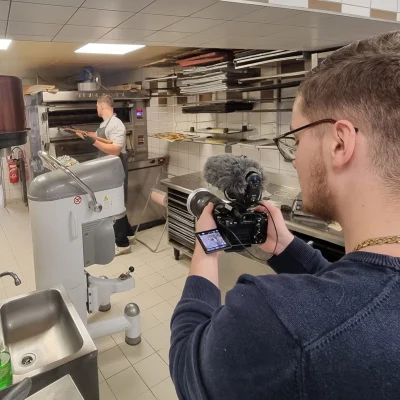 Personne tenant une caméra professionnelle en train de filmer un reportage, illustrant la section vidéo de la page d’accueil